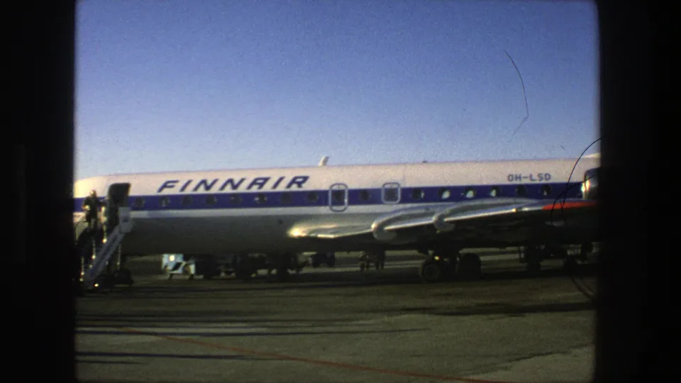 1975 Stockholm airport footage showing a Finnair Super Constellation on the tarmac with blue-and-white livery and boarding stairs nearby.
