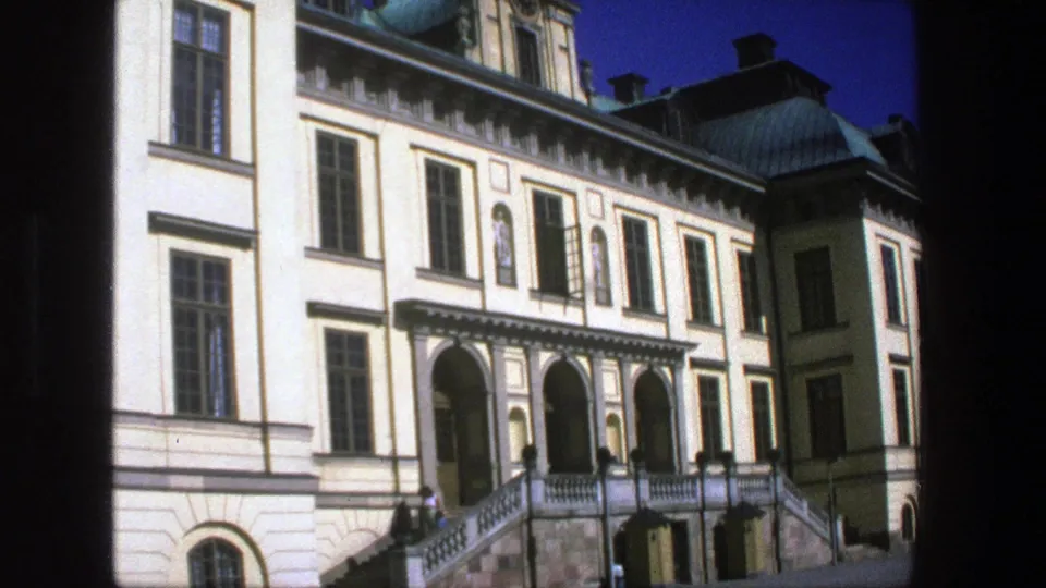 1975 Stockholm frame of a historic building exterior with arched entry bays, a raised staircase, rows of windows, copper roof details, and small people below.