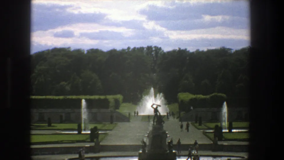 1975 Stockholm travel footage showing a formal garden, central statue, fountains, trees, and small groups of visitors.