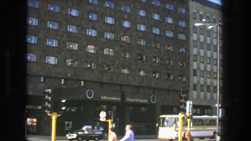 1975 Stockholm view of the Sheraton Stockholm exterior, with pedestrians by the intersection and a yellow bus at the curb.