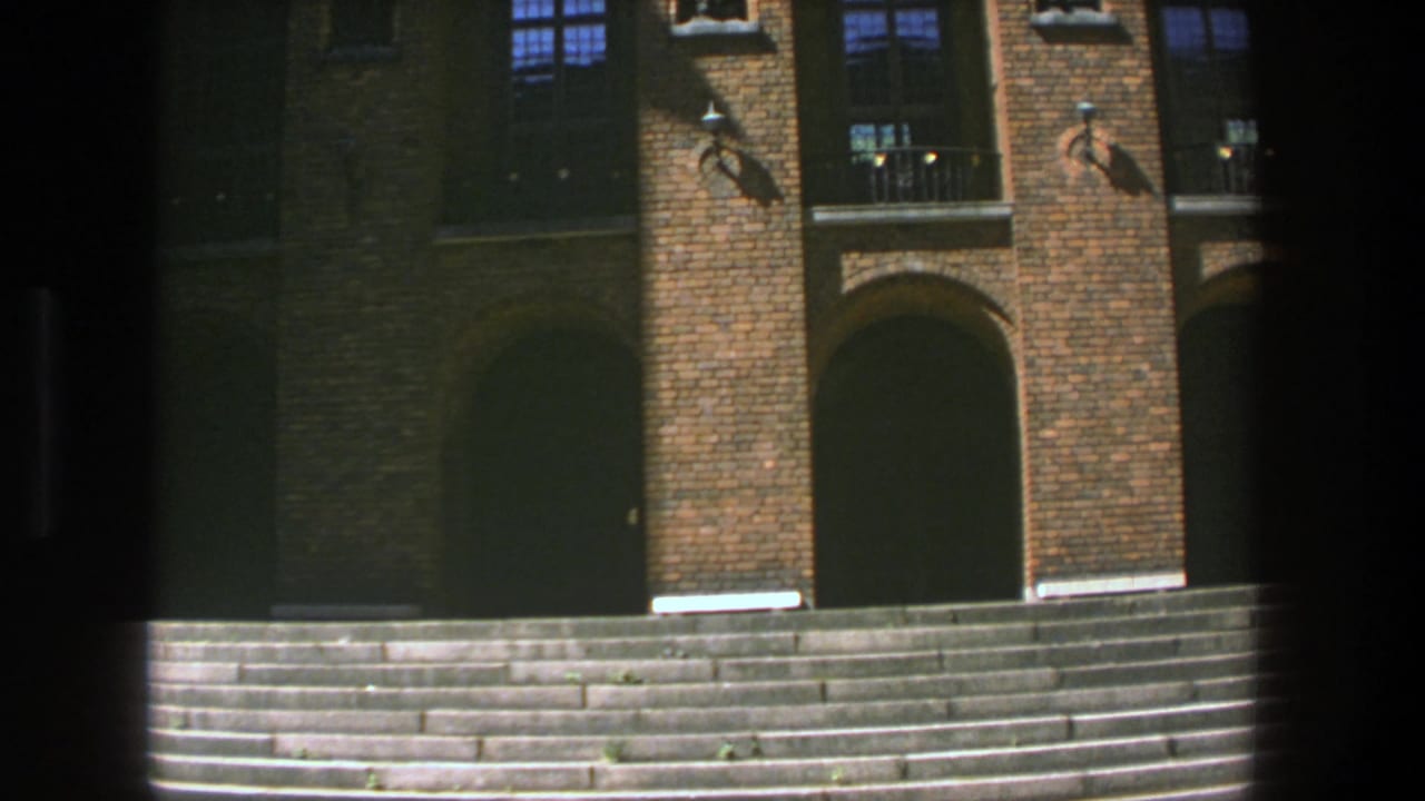 Brick university entrance with arched doorways above wide stone steps.