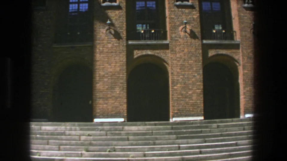 Stockholm university entrance on 8mm film, with brick piers, arched dark doorways, window bays and broad stone steps.
