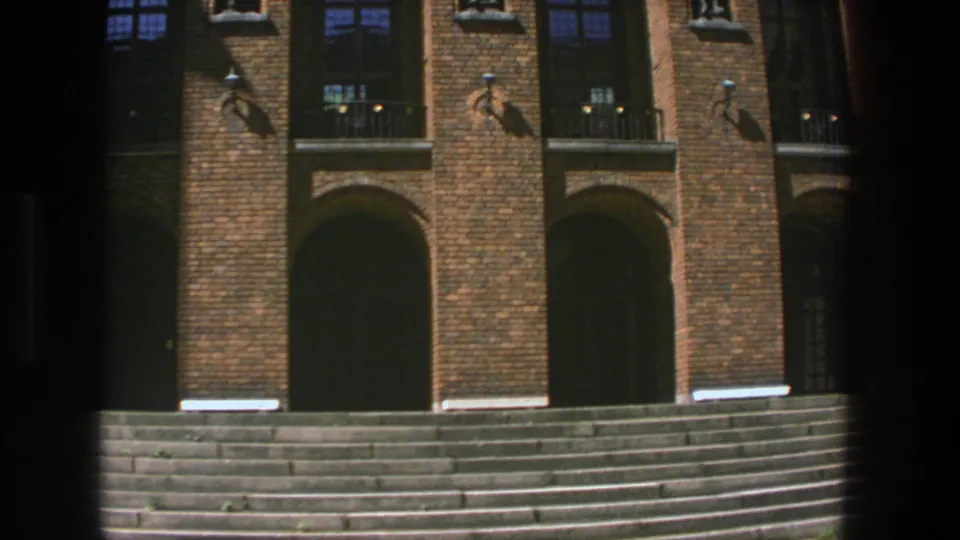 1975 8mm view of a Stockholm university entrance, showing repeating brick bays, dark arched openings and a wide stair landing.