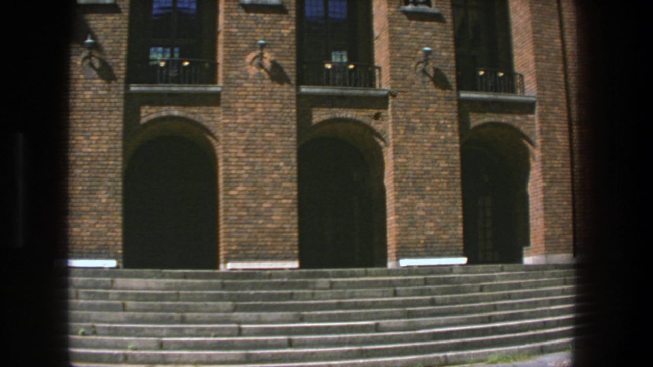 Brick building entrance with broad stone steps and arched doorways.