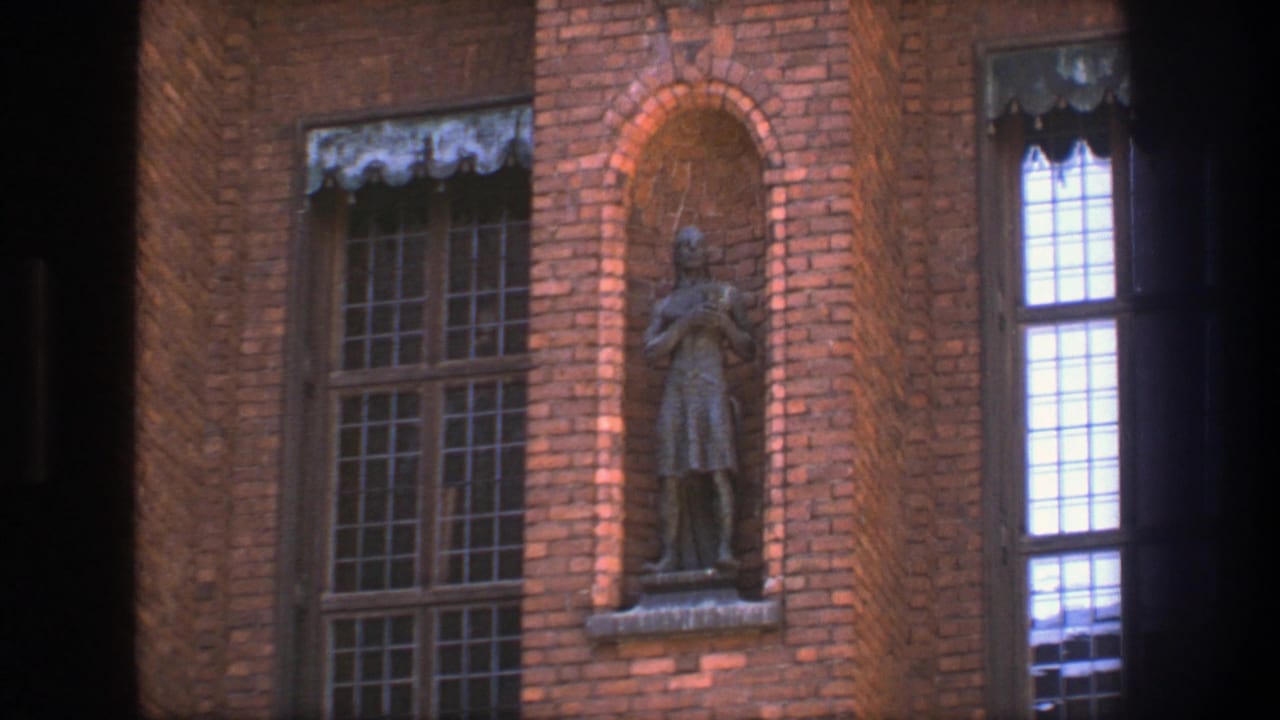 1975 Stockholm 8mm frame showing a brick facade with windows, a recessed statue, and partial dark contact-sheet borders.