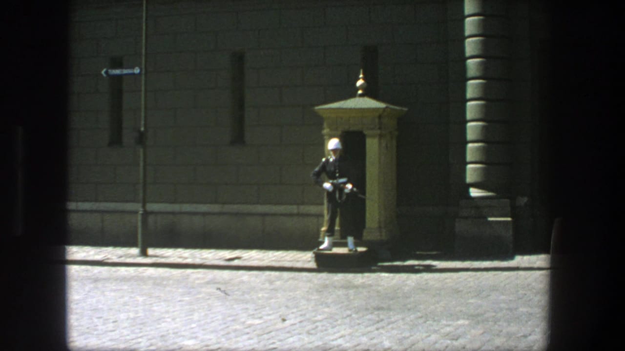 1975 Stockholm street view with a uniformed guard in a white helmet standing near a small sentry box by a stone building.