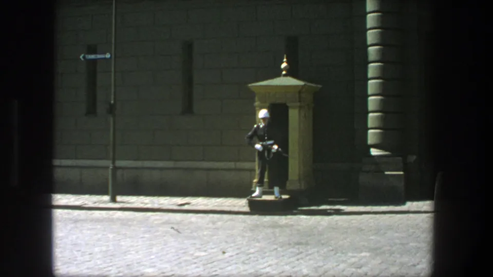 1975 Stockholm street view with a uniformed guard in a white helmet standing near a small sentry box by a stone building.