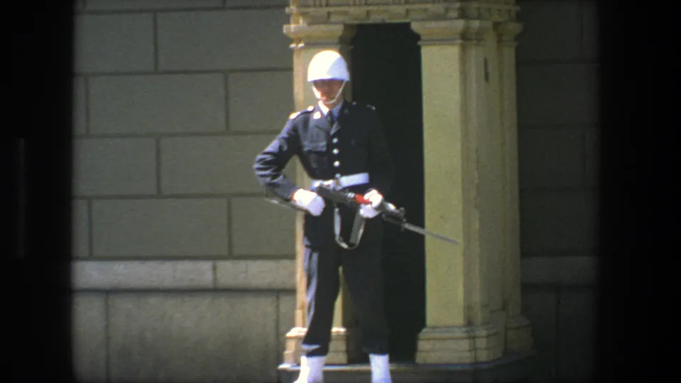 1975 Stockholm frame with a uniformed ceremonial guard standing at attention, rifle angled across the front of the body.