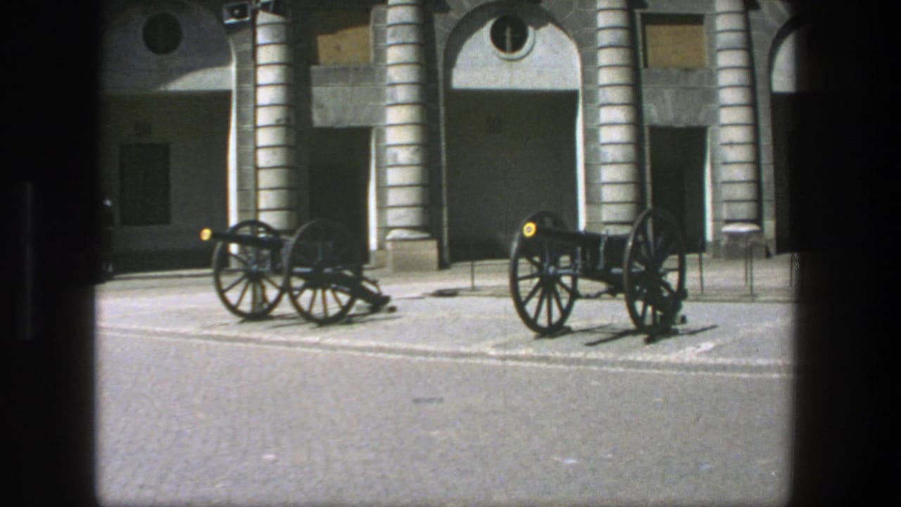 1975 Stockholm 8mm view of paired black cannons on a courtyard, with arched stone bays and circular windows behind them.