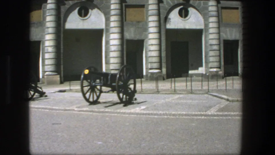 1975 Stockholm 8mm frame showing a historic cannon outside a stone building with arched doorways and columns.