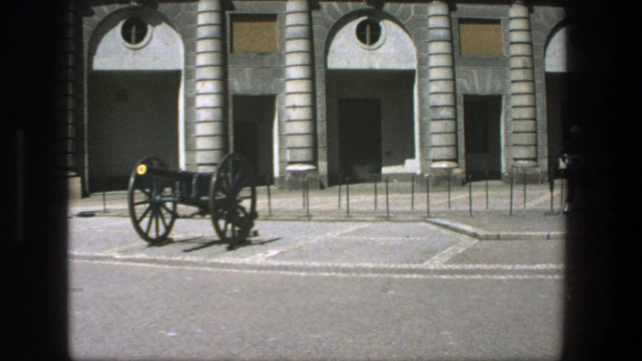 Visitor-shot 1975 Stockholm view of a cannon positioned before a classical stone building with arched entrances.