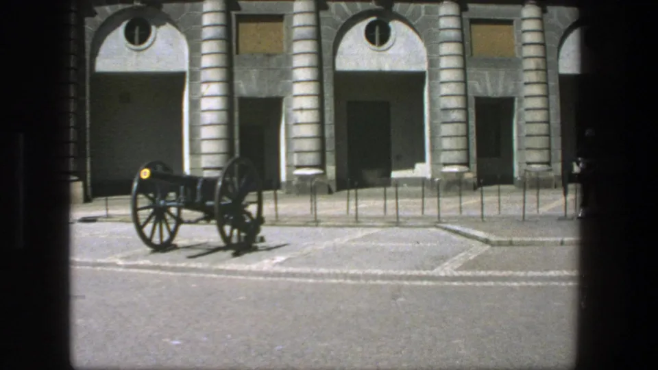 Visitor-shot 1975 Stockholm view of a cannon positioned before a classical stone building with arched entrances.