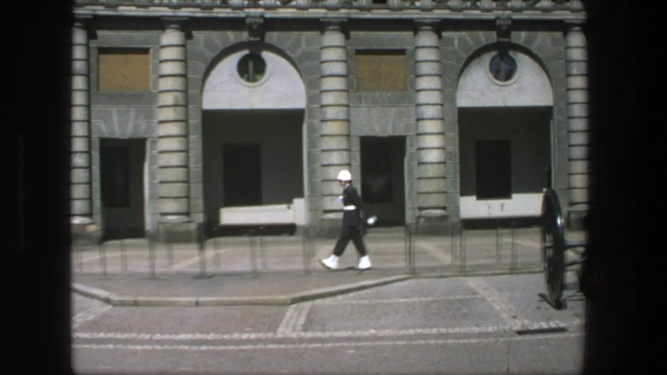 The 1975 Stockholm footage shows the guard marching past a stone facade, arched openings, benches, railings, and a cannon.