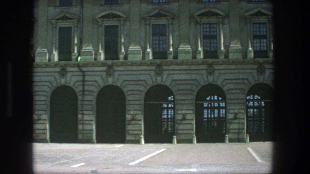 Stone building facade with arched doorways seen through dark foreground framing.