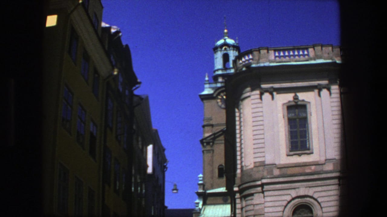 Sunlit tan building with turquoise tower roof beside shadowed street facades.