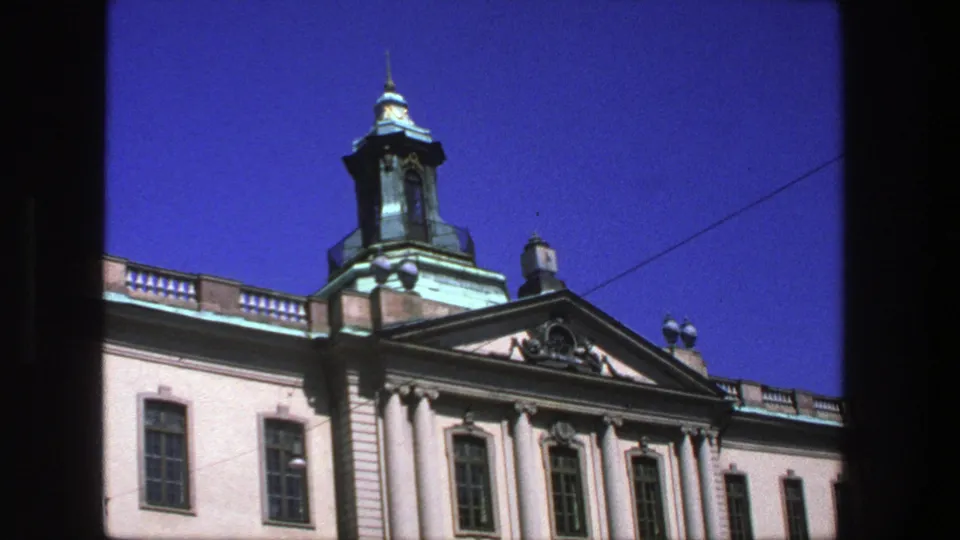 Low-angle Stockholm exterior with classical columns, decorative roofline, cupola, and strong 8mm color saturation.