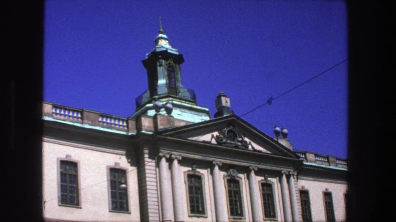 1975 8mm view in Stockholm showing a classical facade with columns, ornate pediment, copper-green dome, and clear blue sky.