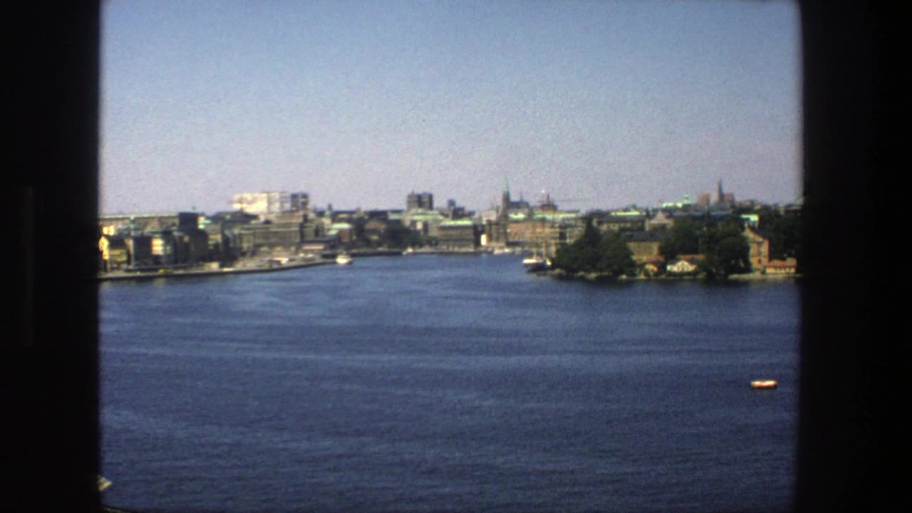 Stockholm waterfront seen across blue water through dark window framing.