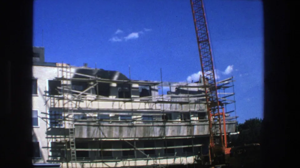 1975 Stockholm 8mm frame showing scaffolding across an unfinished building with a red crane rising beside it.