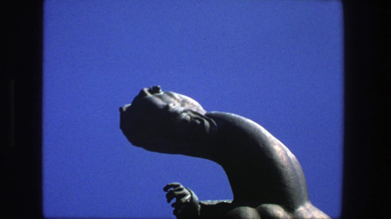 1975 Stockholm 8mm frame with a dark sculptural figure, tilted head, curved neck, and small hand form against blue sky.
