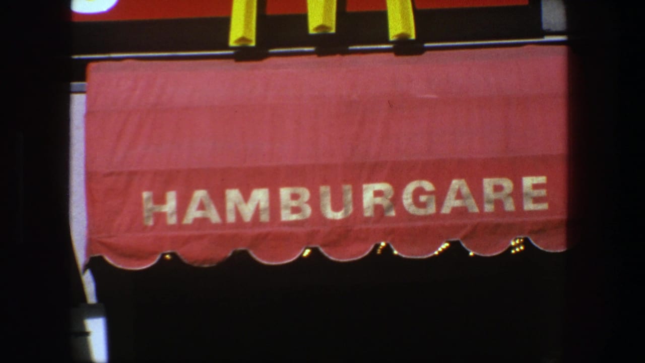 Close view of a red HAMBURGARE awning in 1975 Stockholm home-movie footage.