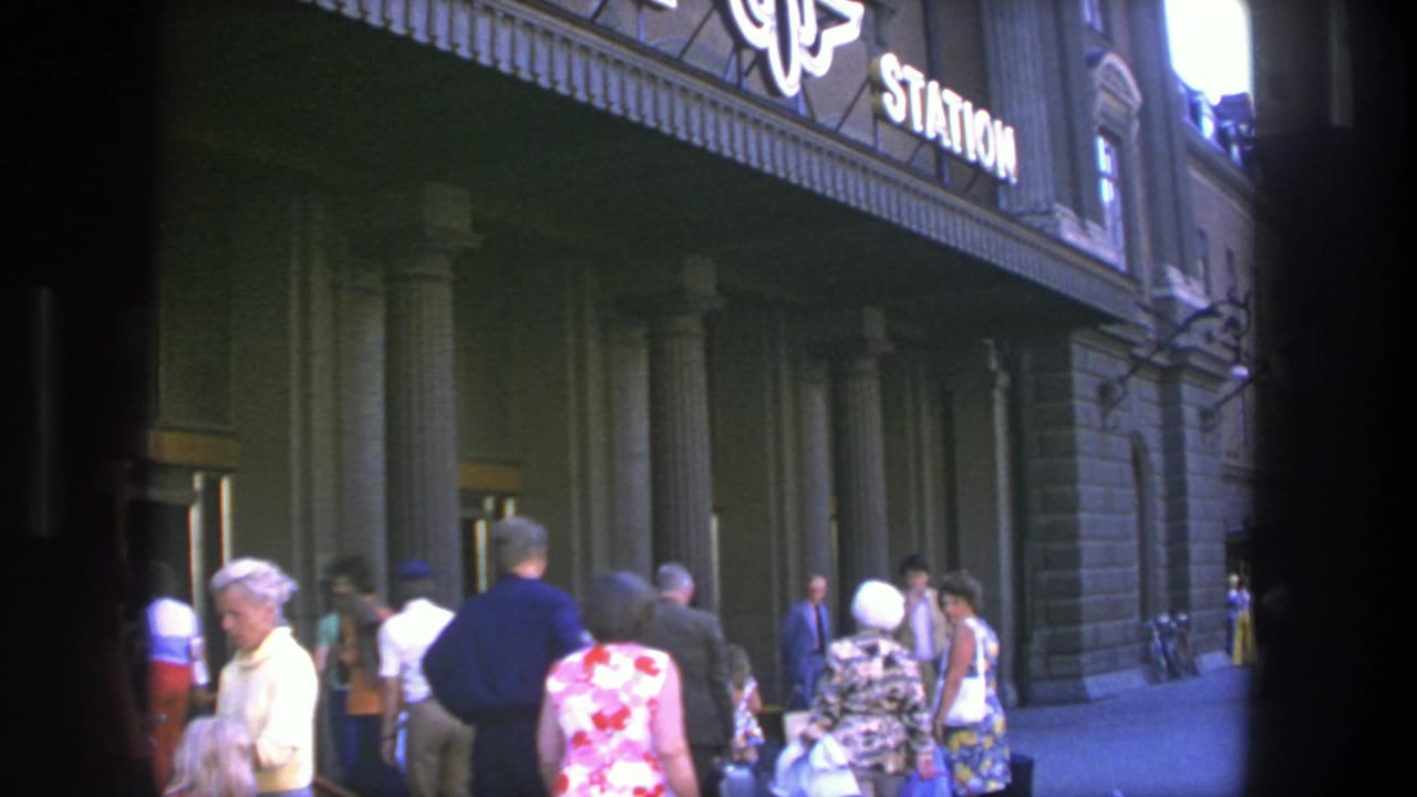 Stockholm, Sweden, 1975: pedestrians in summer clothing pass a columned station entrance with visible signage.