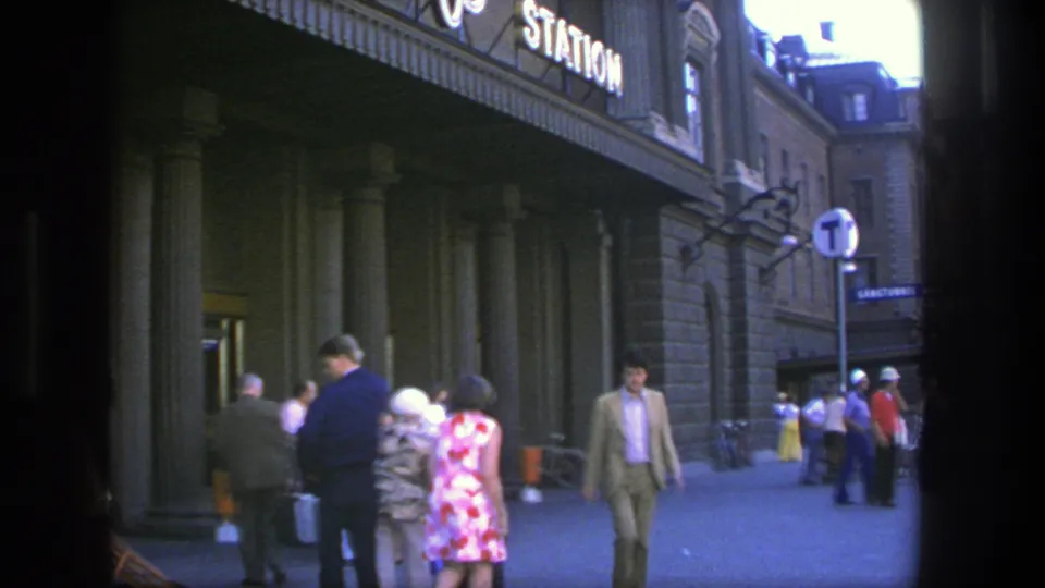 A 1975 Stockholm street view shows a suited man approaching while other pedestrians move beside the station facade.
