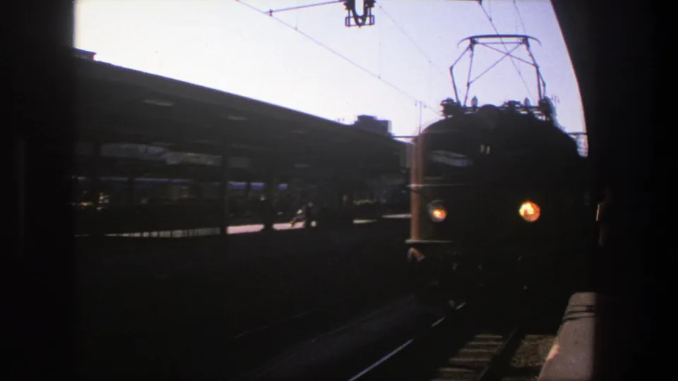 1975 Stockholm station footage showing the train close to the platform, headlights glowing in high-contrast 8mm exposure.
