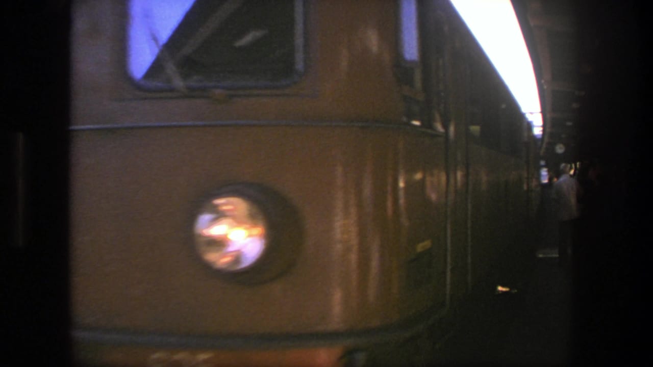 Close handheld view of a yellow passenger train nose at a Stockholm platform, with the headlight reflecting light.