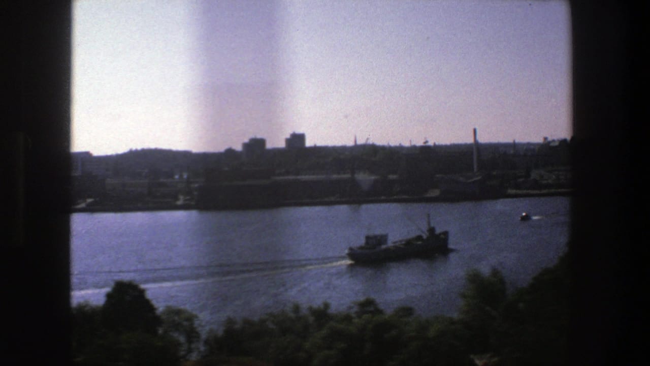 Harbor water with a small vessel moving past a silhouetted city shoreline.