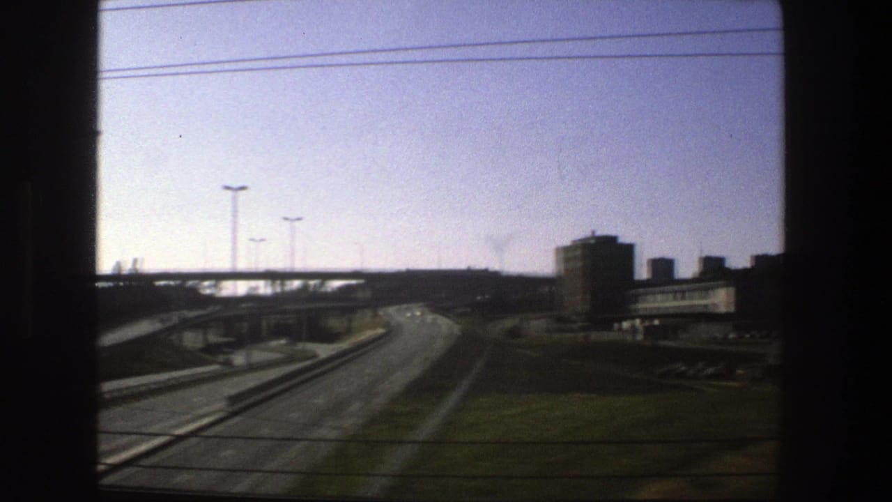 Stockholm road interchange in 1975, showing curving lanes, overpasses, streetlights, and block-like buildings from a vehicle window.
