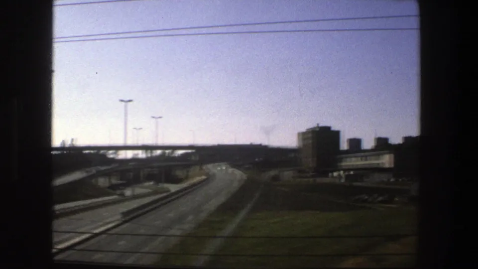 Stockholm road interchange in 1975, showing curving lanes, overpasses, streetlights, and block-like buildings from a vehicle window.