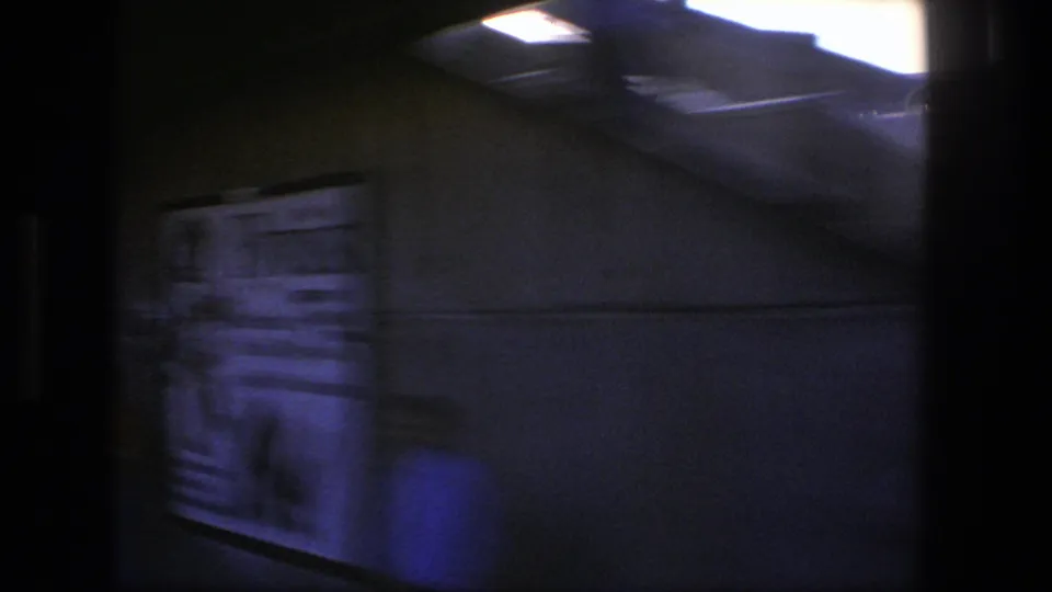 A blurred 1975 Stockholm rail-side view shows a freight car or trackside structure passing close to the train window.