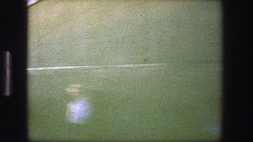 Close, abstracted train-window frame with greenish surface, reflected light, visible grain, and scratches from the 8mm scan.