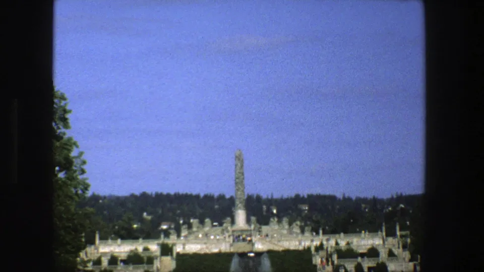 Late clip frame of a Stockholm monument and public park on 8mm, with saturated blue sky and distant visitors near the grounds.