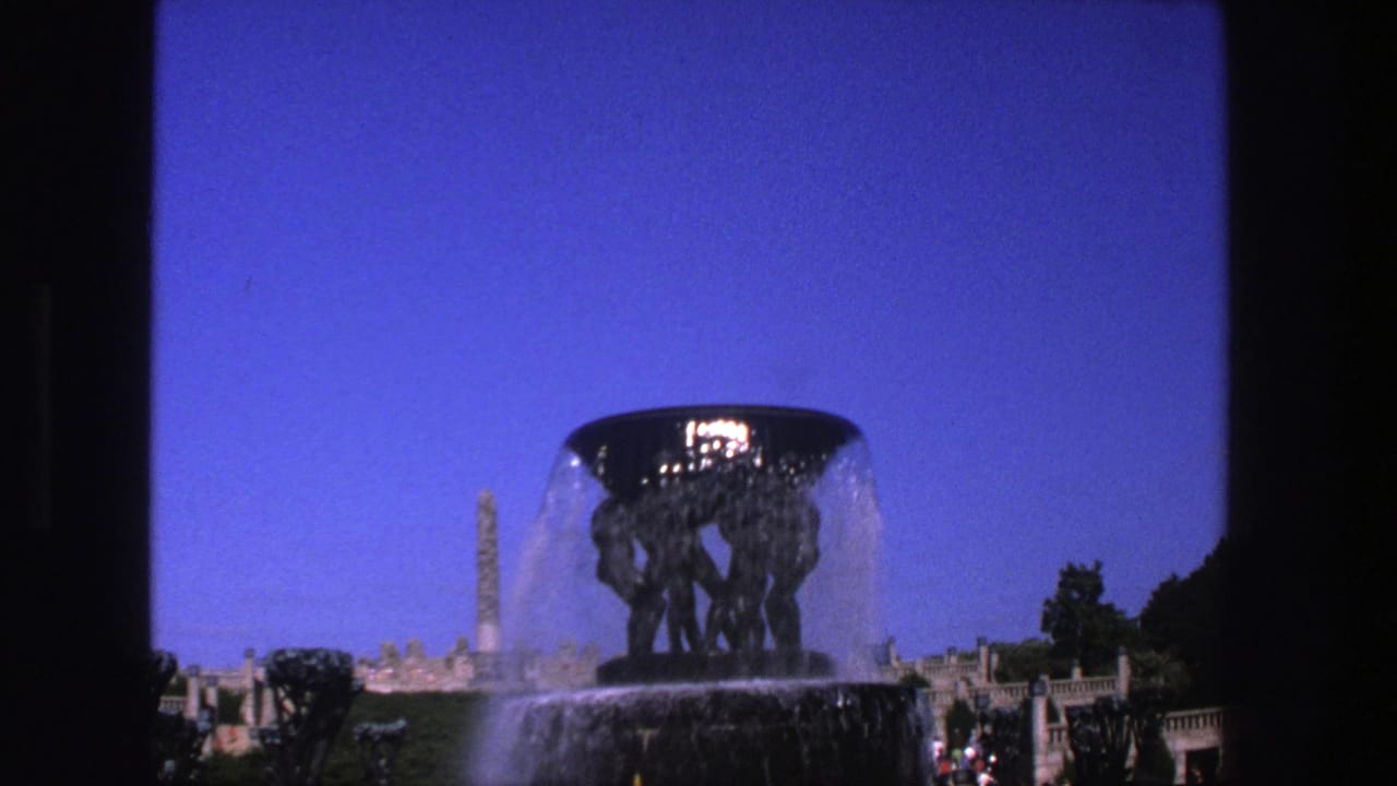 Fountain and water spray framed against blue sky, with distant visitors near the lower right.