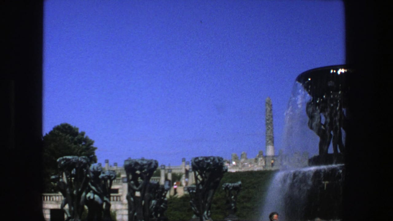 1975 Stockholm view of a dark fountain basin, sculptural figures, cascading water, trees, terrace railings, and a distant monument.