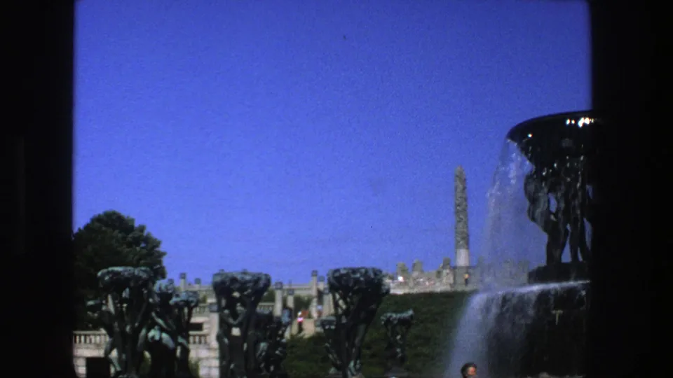 1975 Stockholm view of a dark fountain basin, sculptural figures, cascading water, trees, terrace railings, and a distant monument.