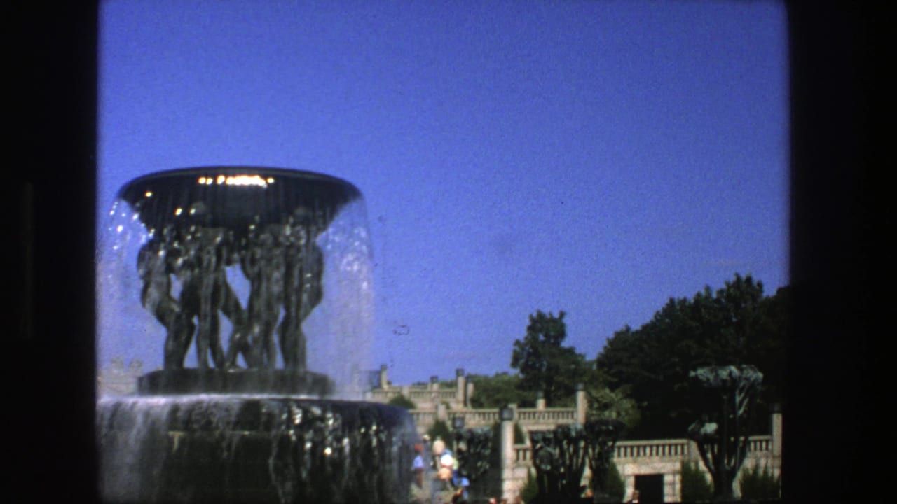 Large sculptural fountain with water cascading in a sunny park setting.