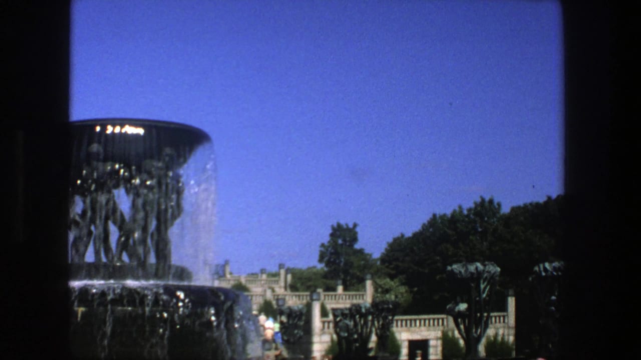 1975 Stockholm view of the fountain from a visitor perspective, with water spilling over the rim and trees behind it.