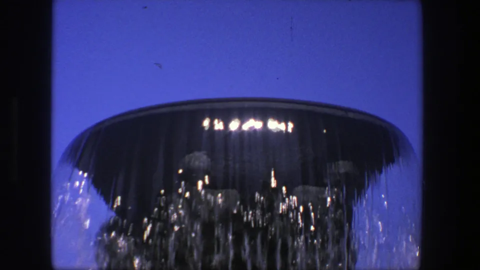 Final close frame of the 1975 Stockholm fountain, with water streaming from the bowl and sunlight sparkling across the falling sheet.