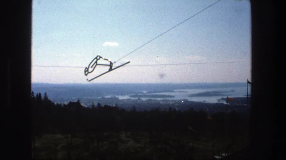 Stockholm 1975 8mm frame with a cable car hanger against the sky and archipelago scenery in the distance.