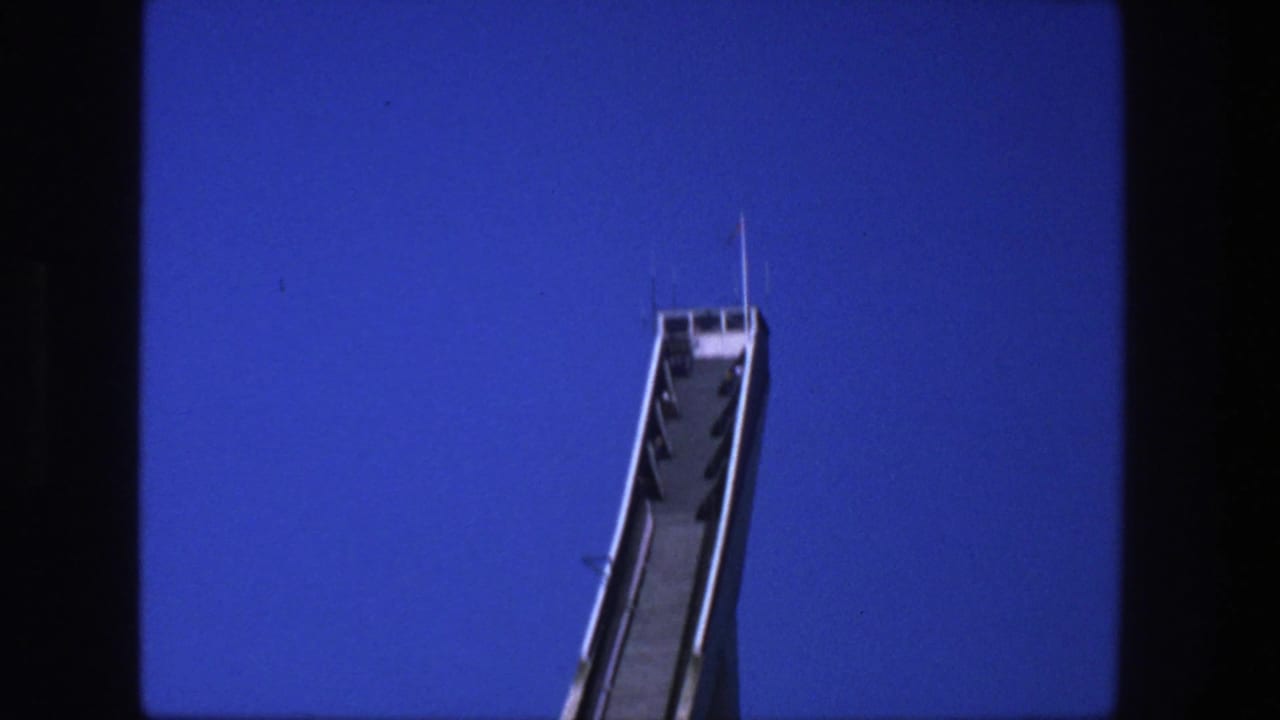 Upper portion of the Stockholm ski jump ramp appears at a diagonal, with railings and platform details visible against blue sky.