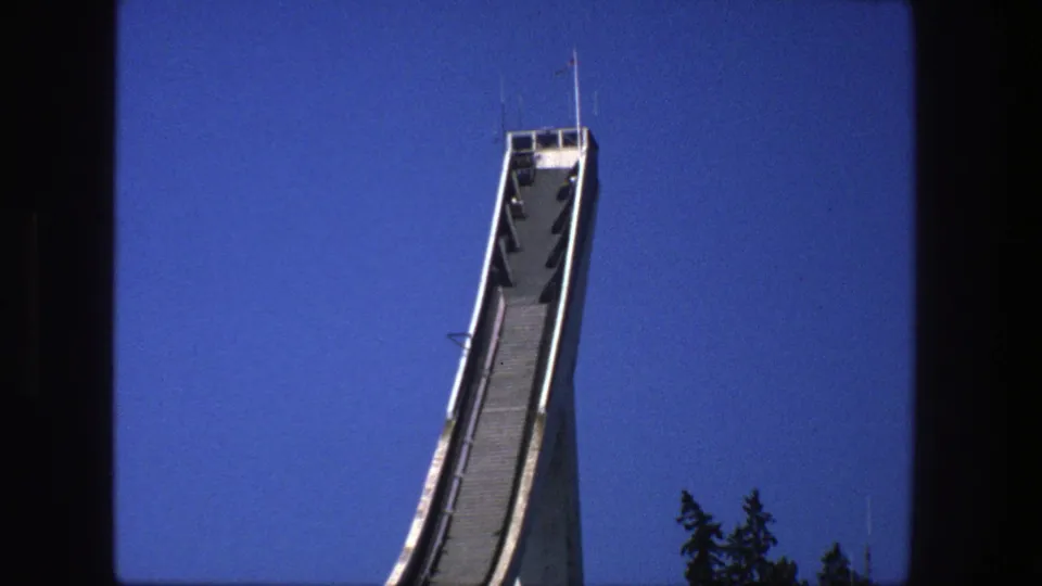 1975 Stockholm 8mm view revealing more of the white ski jump ramp, its support, and dark treetops below.