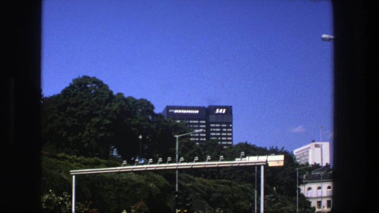 Blue sky over trees, a SAS-marked building, streetlights, and a metal gantry.