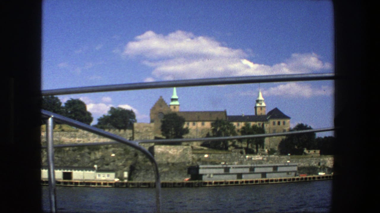 Historic stone waterfront complex seen across water through boat railings.