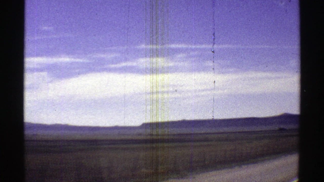 Desert horizon and roadside curve viewed through a scratched 8mm frame.