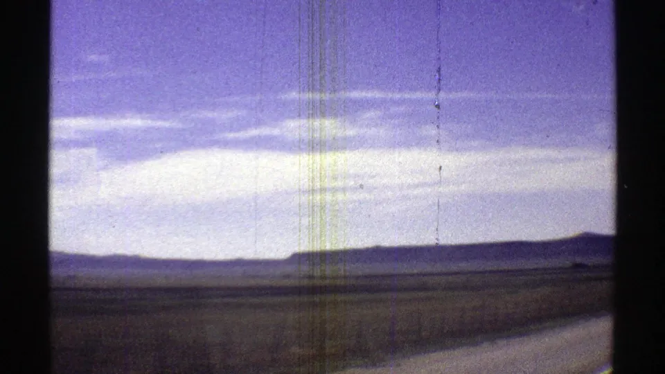 Arizona desert highway scenery from 1969, with a low mesa-like horizon, pale clouds, and a road edge entering the lower right.