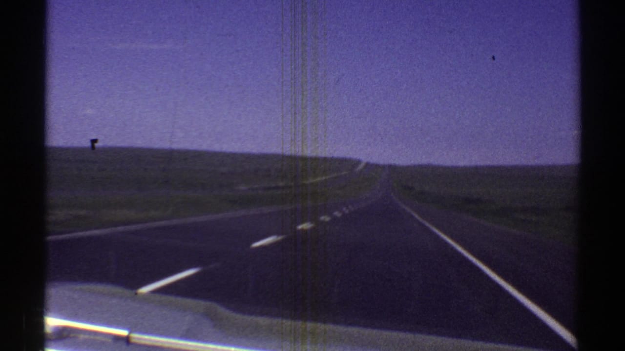 1969 Arizona 8mm view from a car looking down a long, straight highway under a pale sky.