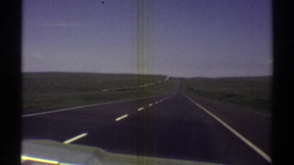 Car-mounted or dashboard view of an Arizona desert highway, with road markings leading toward a distant horizon.
